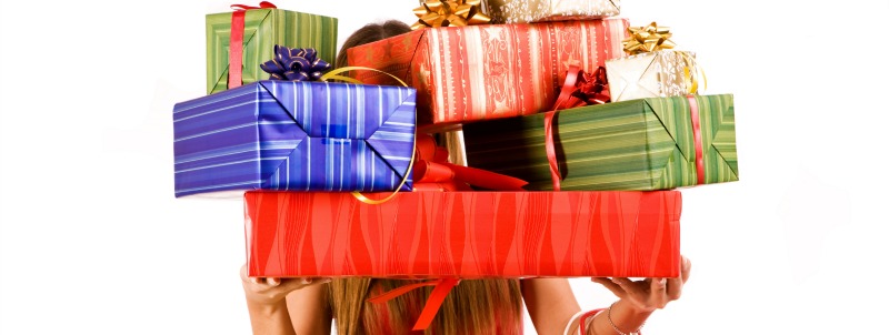 woman holding several christmas gifts covering her face and upper body