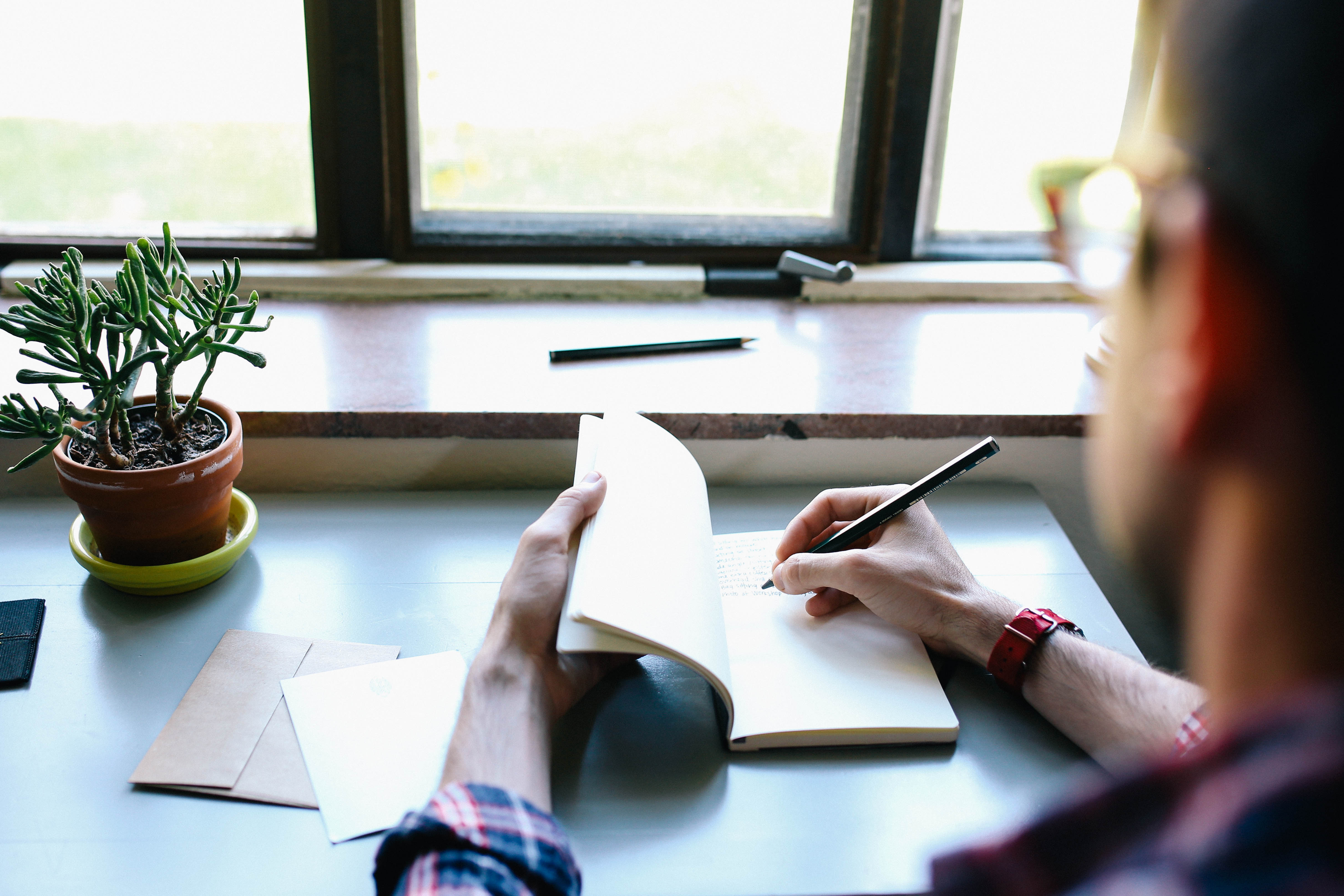 male business owner in glasses writing in notebook